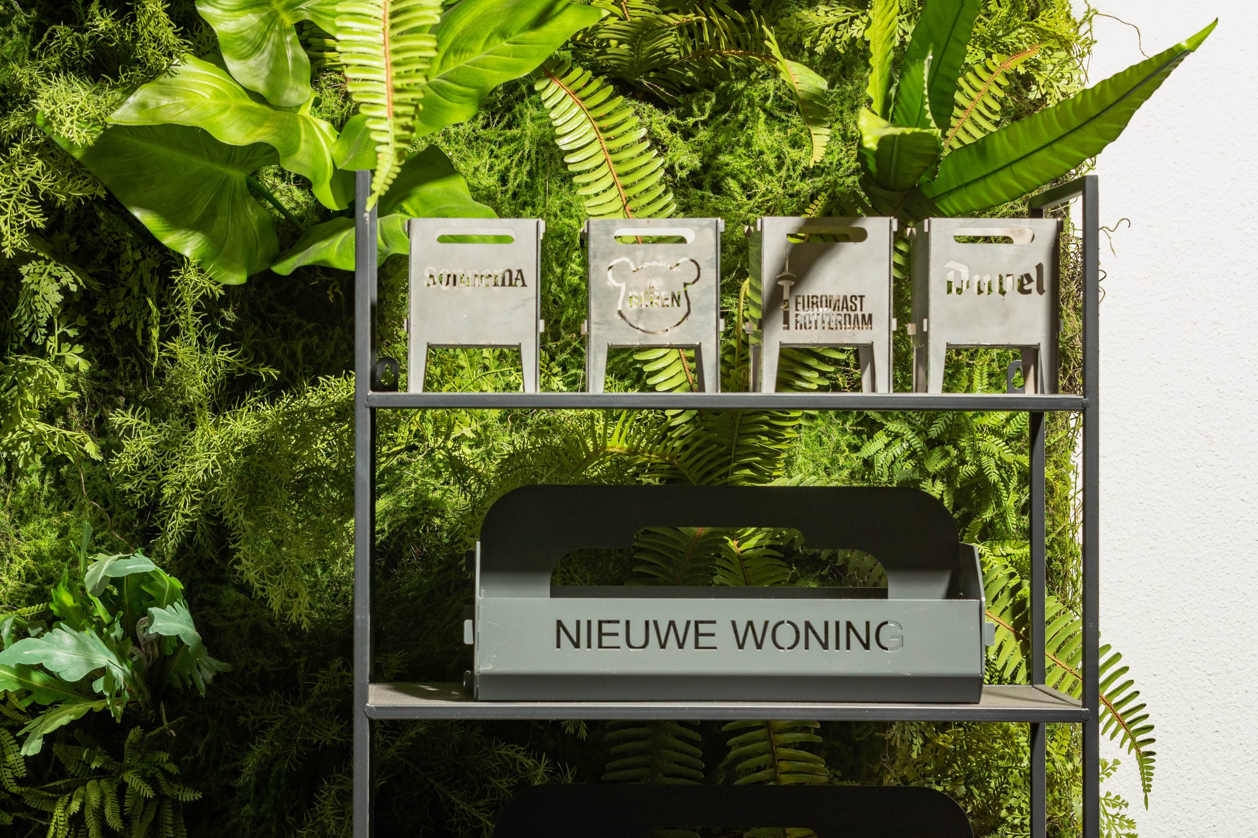 Stalen kratjes van Lokaalverrast op een rek tegen een plantenwand