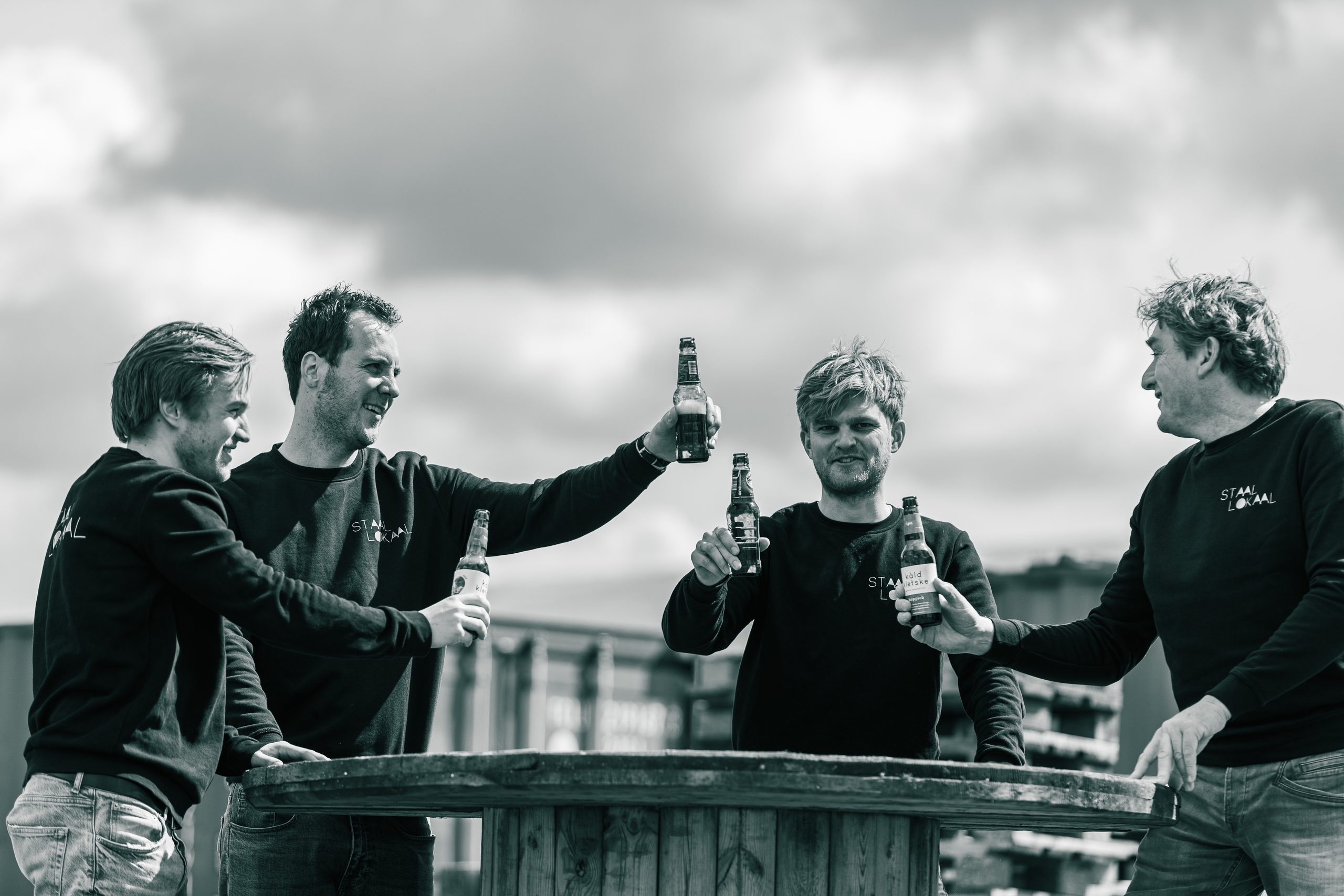 Team van Lokaalverrast proost met een biertje aan een statafel buiten