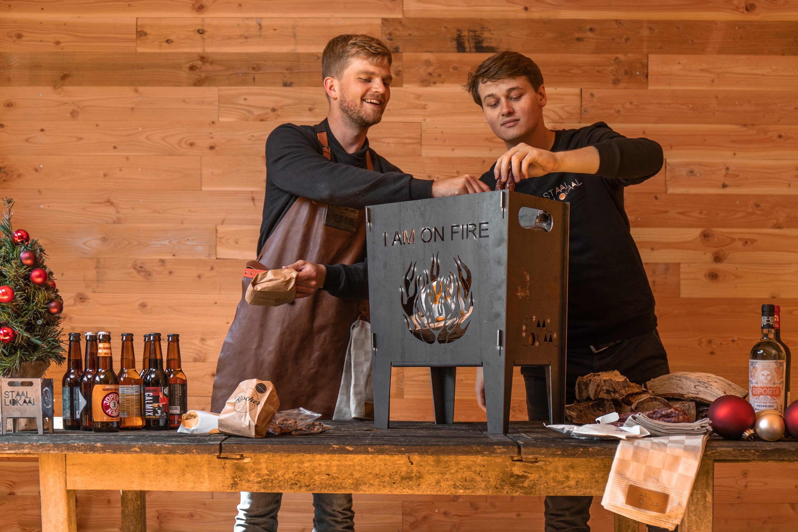 Twee medewerkers van Lokaalverrast aan tafel met een stalen vuurkorf en lokaal bier