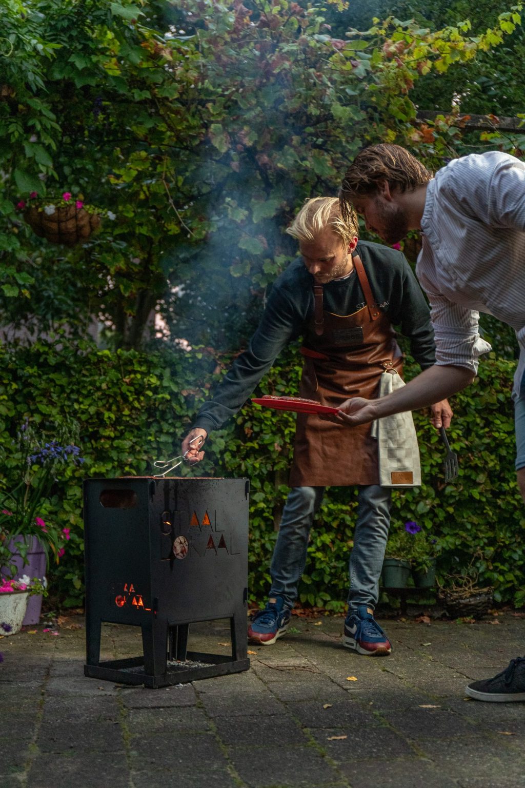 Twee mannen barbecueën op een stalen vuurkorf van Lokaalverrast in de tuin